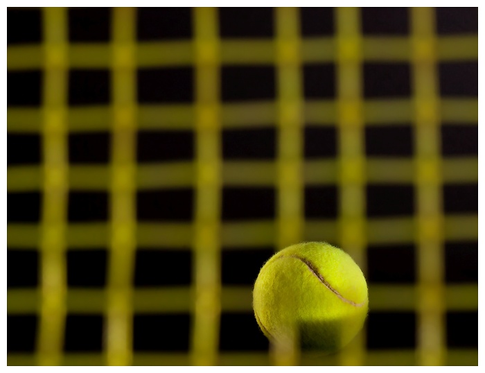 Tennisball trifft die Besaitung vom Tennisschläger vor dunklem Hintergrund