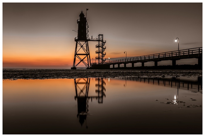 Blick auf den Leuchtturm Obereversand mit Spiegelung im Wasser