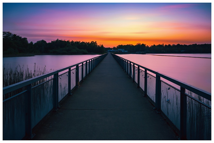 Blick über die lange Brücke am Norderstedter Stadtparksee bei rotem Sonnenuntergang