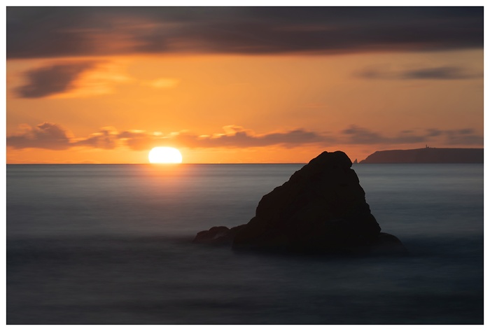 Wunderschöner Blick auf einen Felsen im Wasser im roten Sonnenuntergang