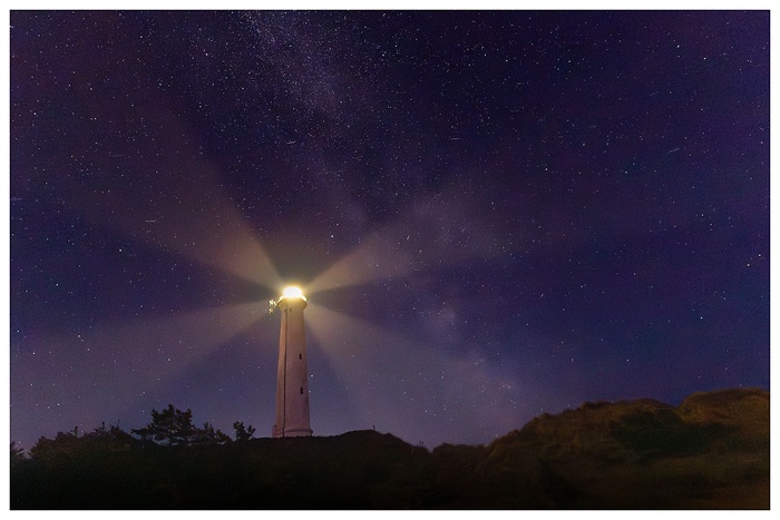 Blick auf den wunderschönen Nachthimmel mit Milchstraße über dem Leuchtturm in Dänemark