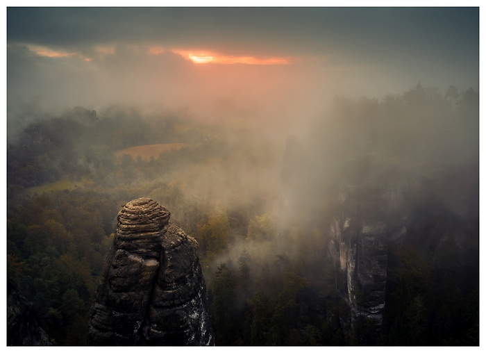 Blick auf Felsformationen im rötlichen Sonnenaufgang bei der Basteibrücke im Elbsandsteingebirge