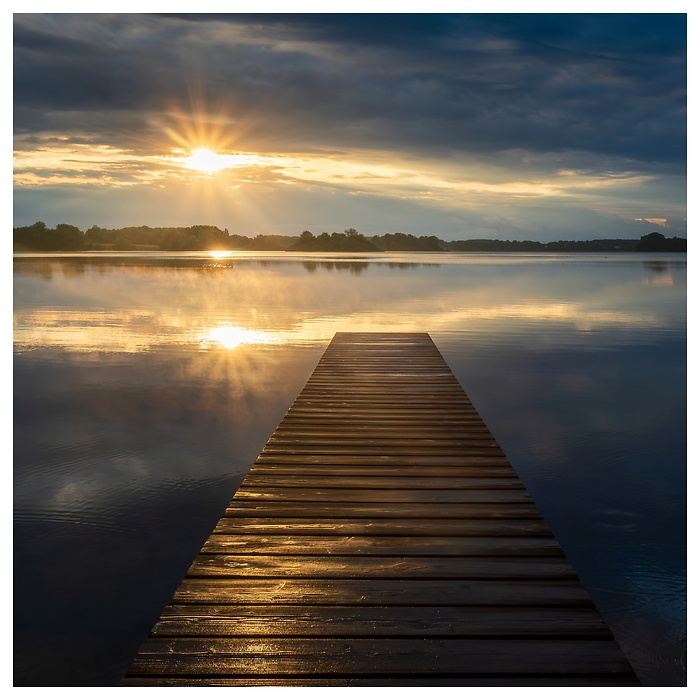 Blick auf einen Steg am See im goldenen Sonnenuntergang